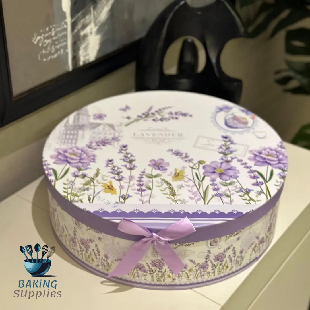 Round decorative box with floral design and pink ribbon on a surface, with 'Baking Supplies' logo in the corner.