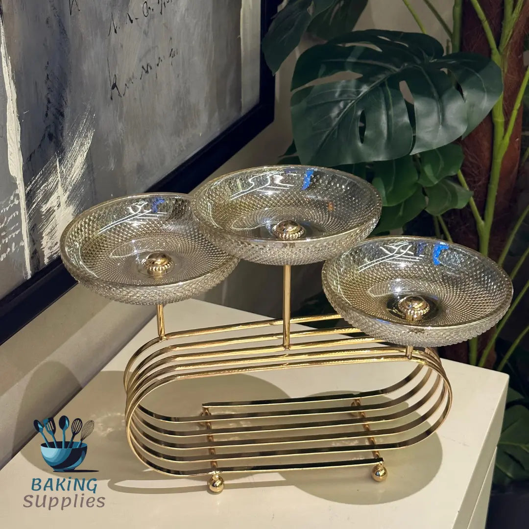 Gold three-tiered stand with decorative glass bowls on a white surface.
