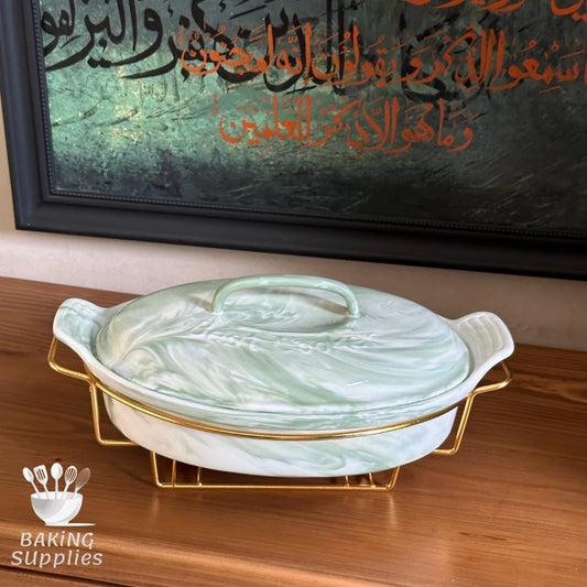Marble-patterned baking dish with gold accents on a wooden surface, framed calligraphy in the background.