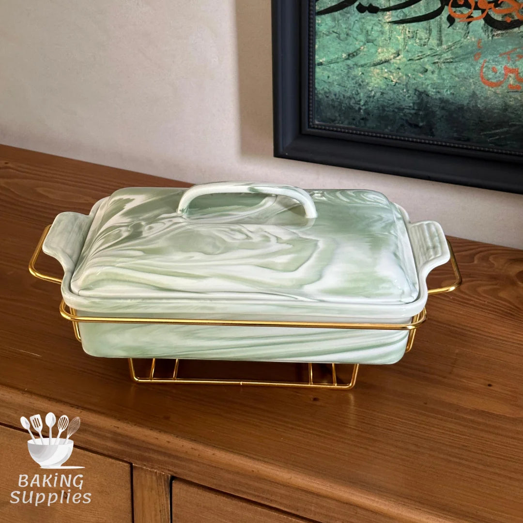 Green ceramic baking dish with gold handles on a wooden surface, with 'Baking Supplies' logo.
