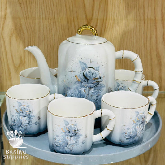 Ceramic teapot and cups with floral design on a wooden surface